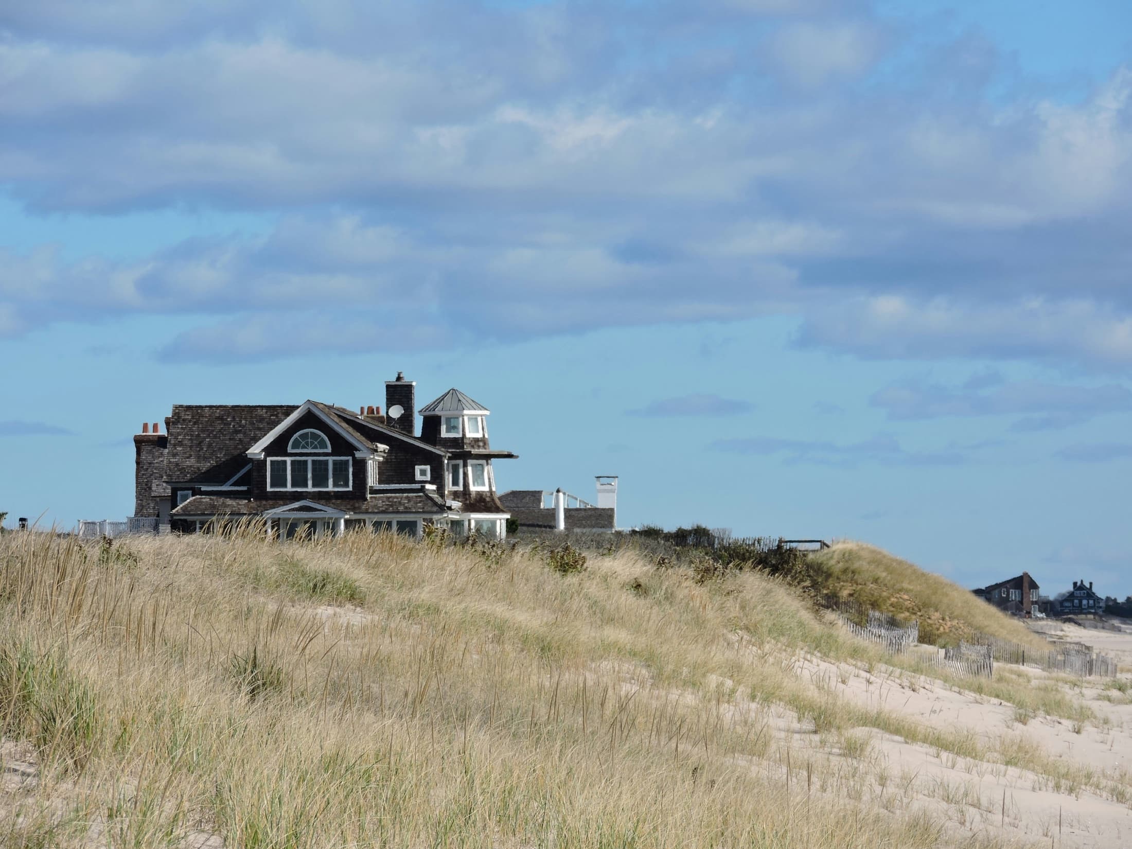 Coastal home surrounded by beach grass beneath a blue sky