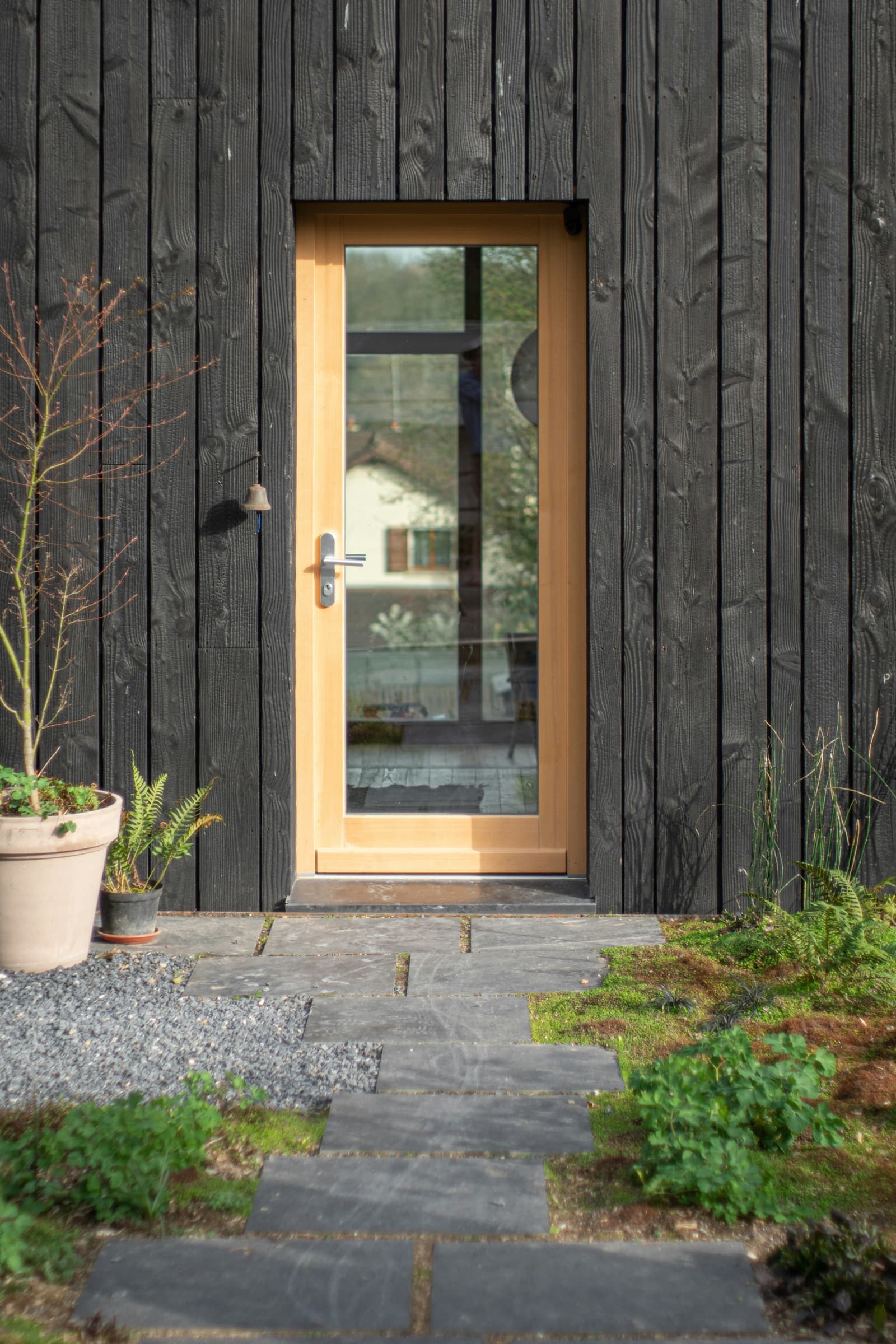 Contemporary glazed entry door in a dark timber facade